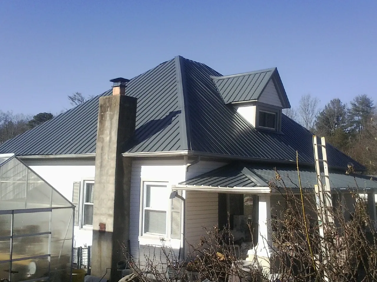 Dark blue standing seam metal roof on a white farmhouse with dormer — Slate & Tile Roof Repair by Roofing Brothers in Danevang