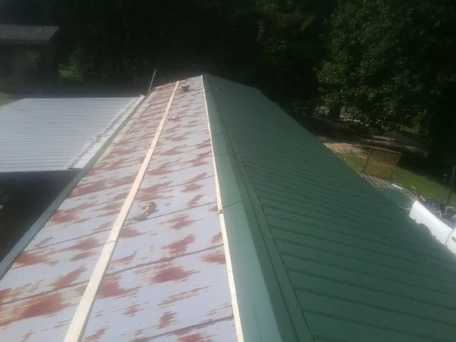 Old rusted panels beside newly installed green metal roofing — Wind Damage Roof Repair by Roofing Brothers in Danevang