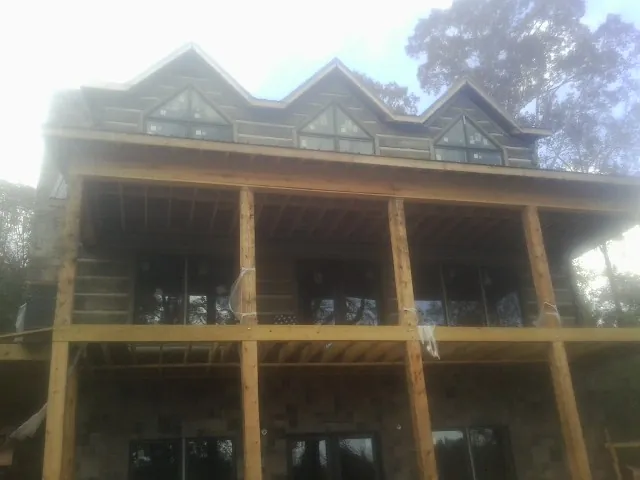 Dormers and porch framing on a large log home under construction — Roof Coating work by our crew in Danevang