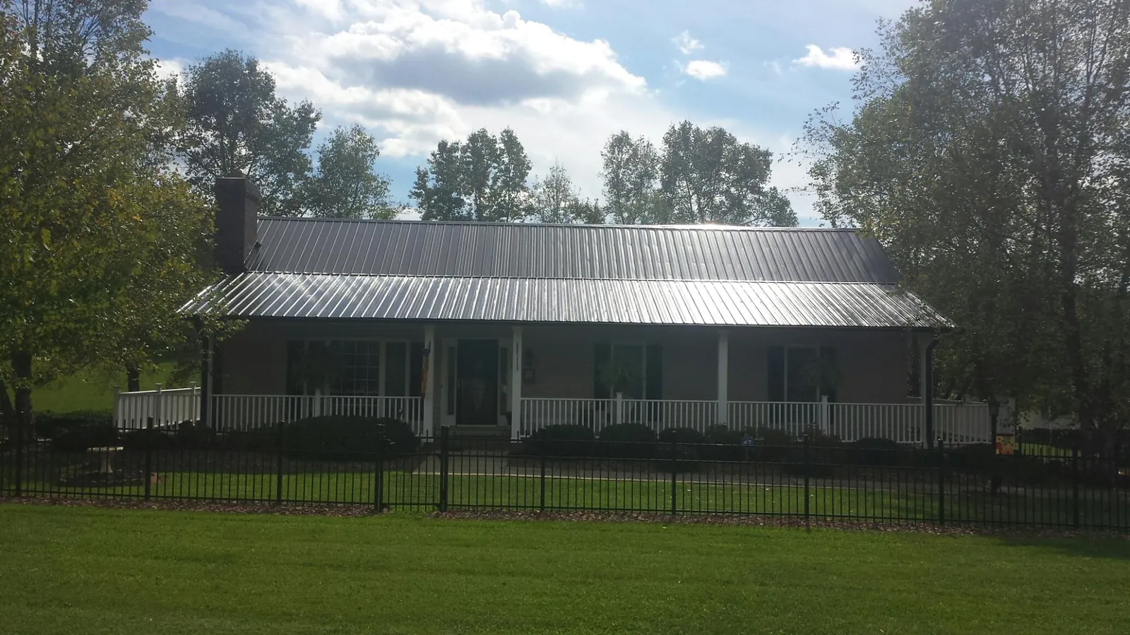 Gray metal roof on a brick ranch with a full width front porch — Gutter Guard Installation work by our crew in Danevang