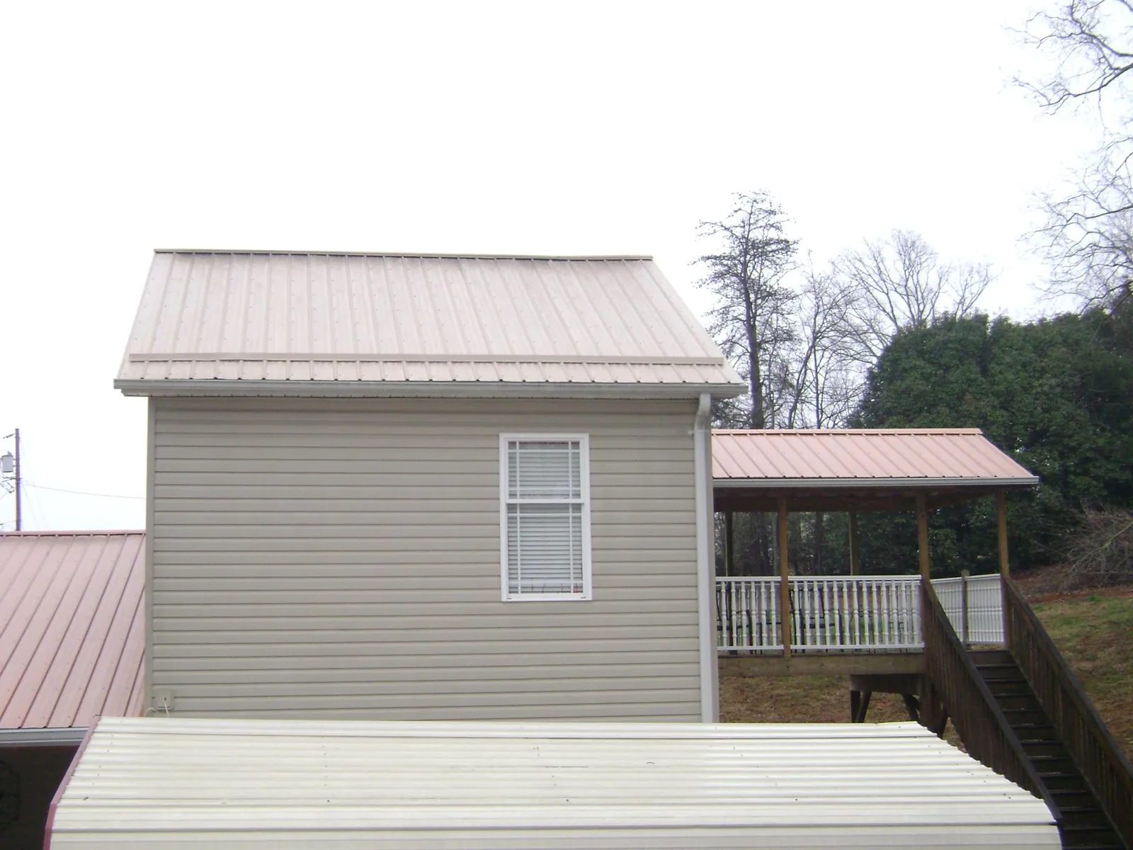 Tan metal roofs on a two story addition and attached porch, from a Roof Replacement job in Danevang