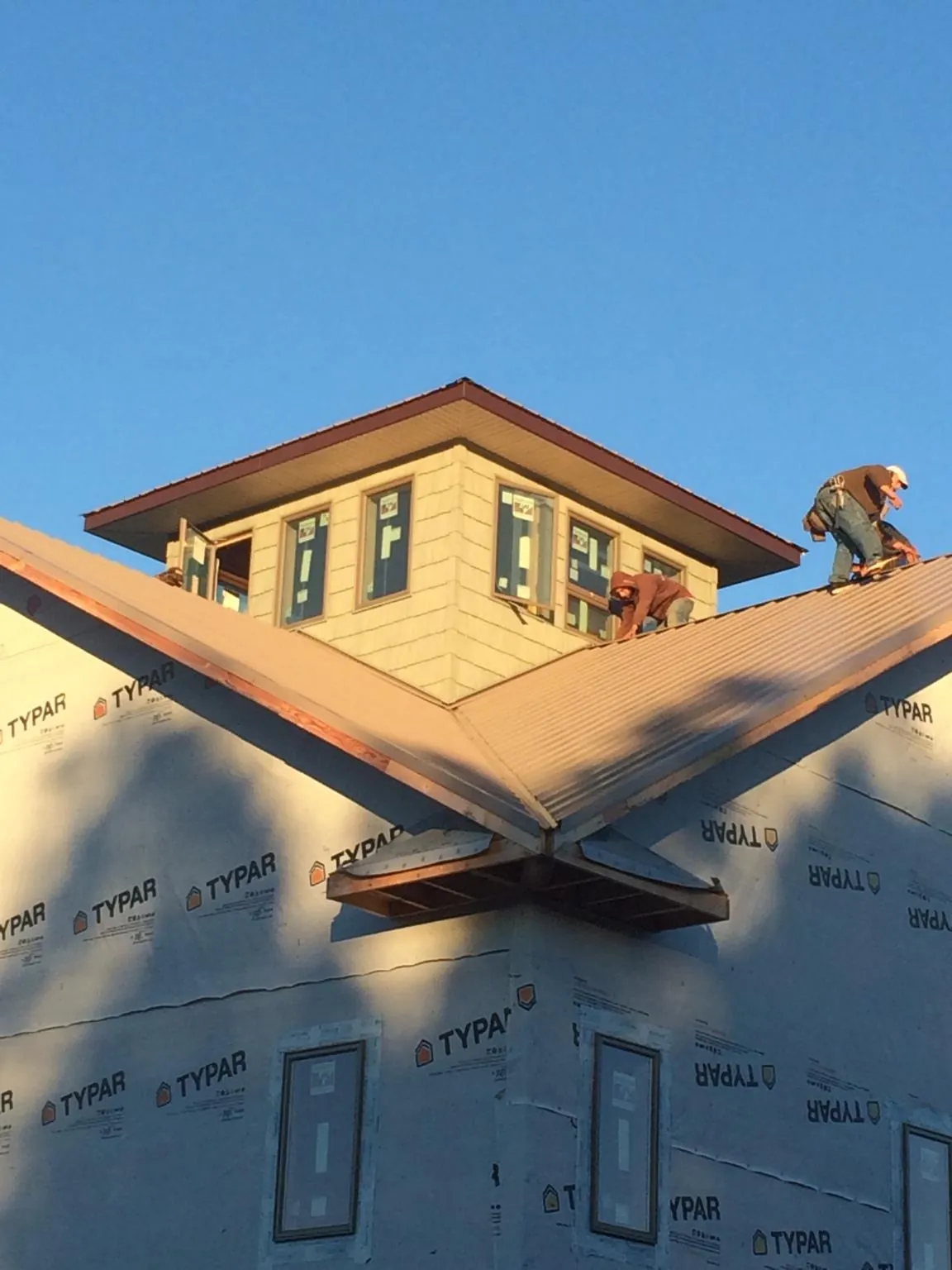 Roofers working around a rooftop cupola on a new metal roof at sunset — Roof Waterproofing in Danevang by Roofing Brothers